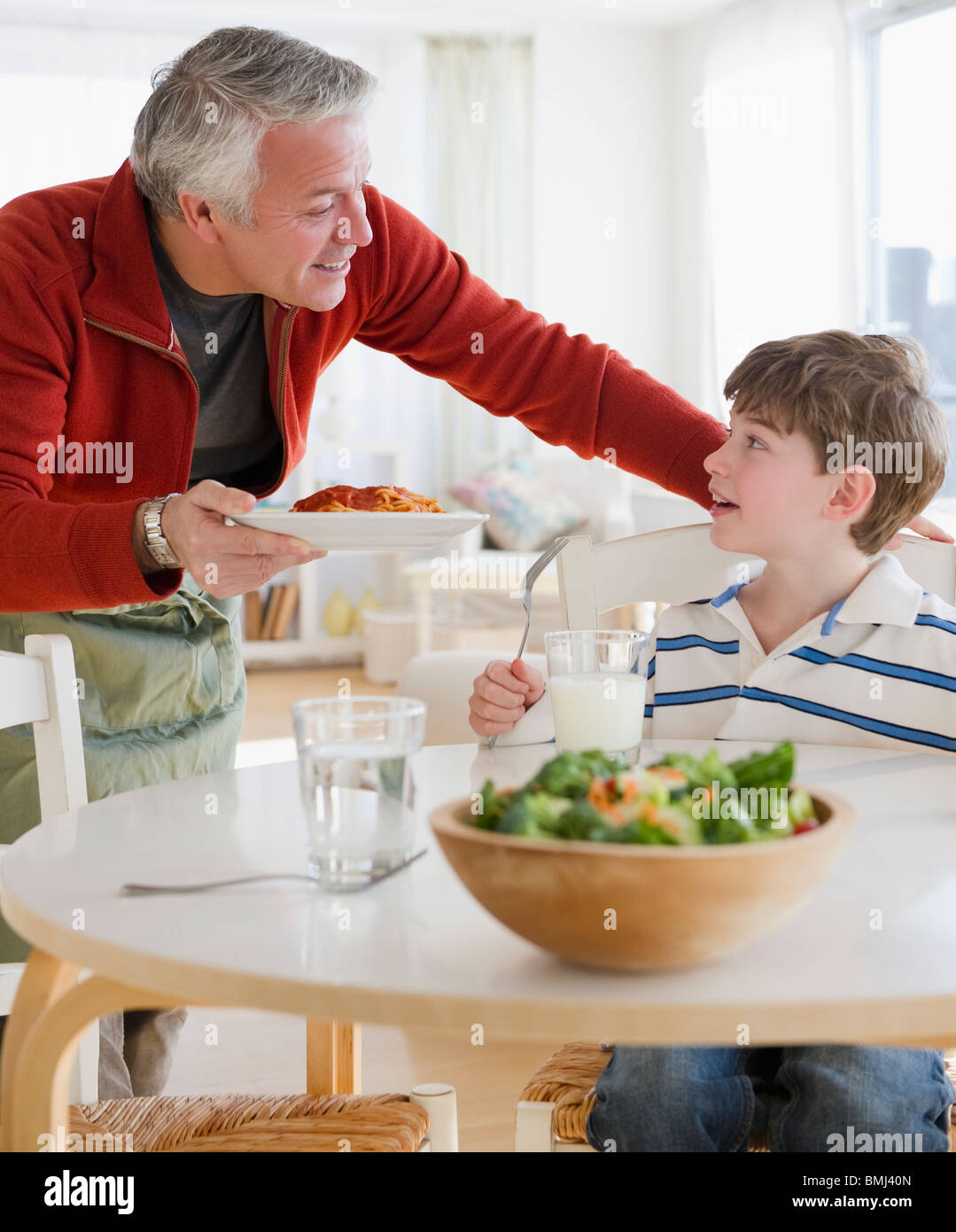 Father giving plate of spaghetti to son Stock Photo