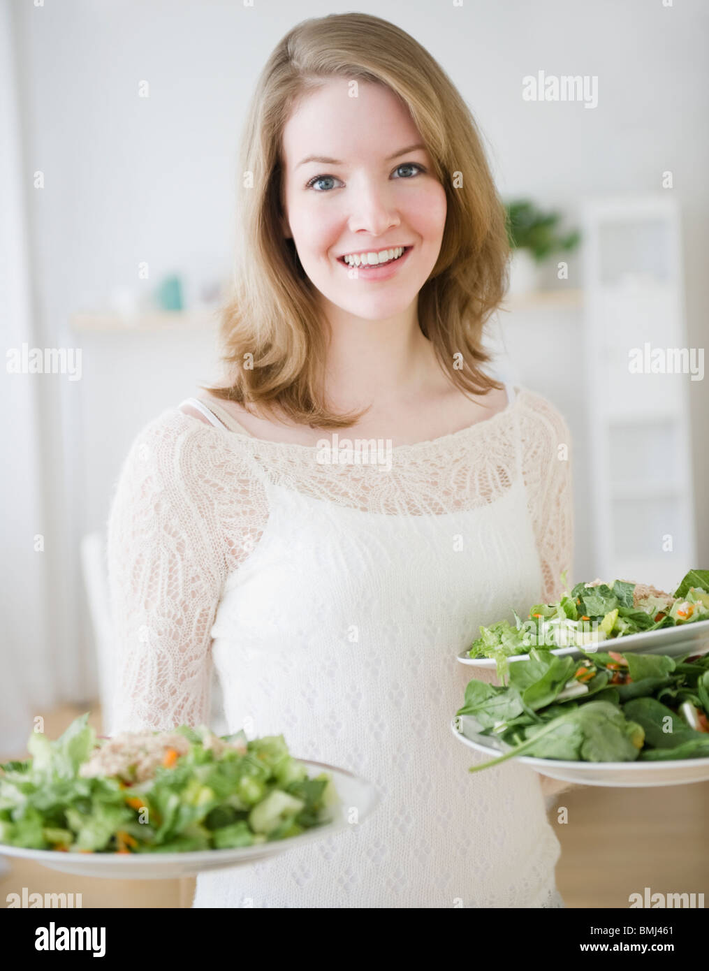 Woman carrying plates of salad Stock Photo