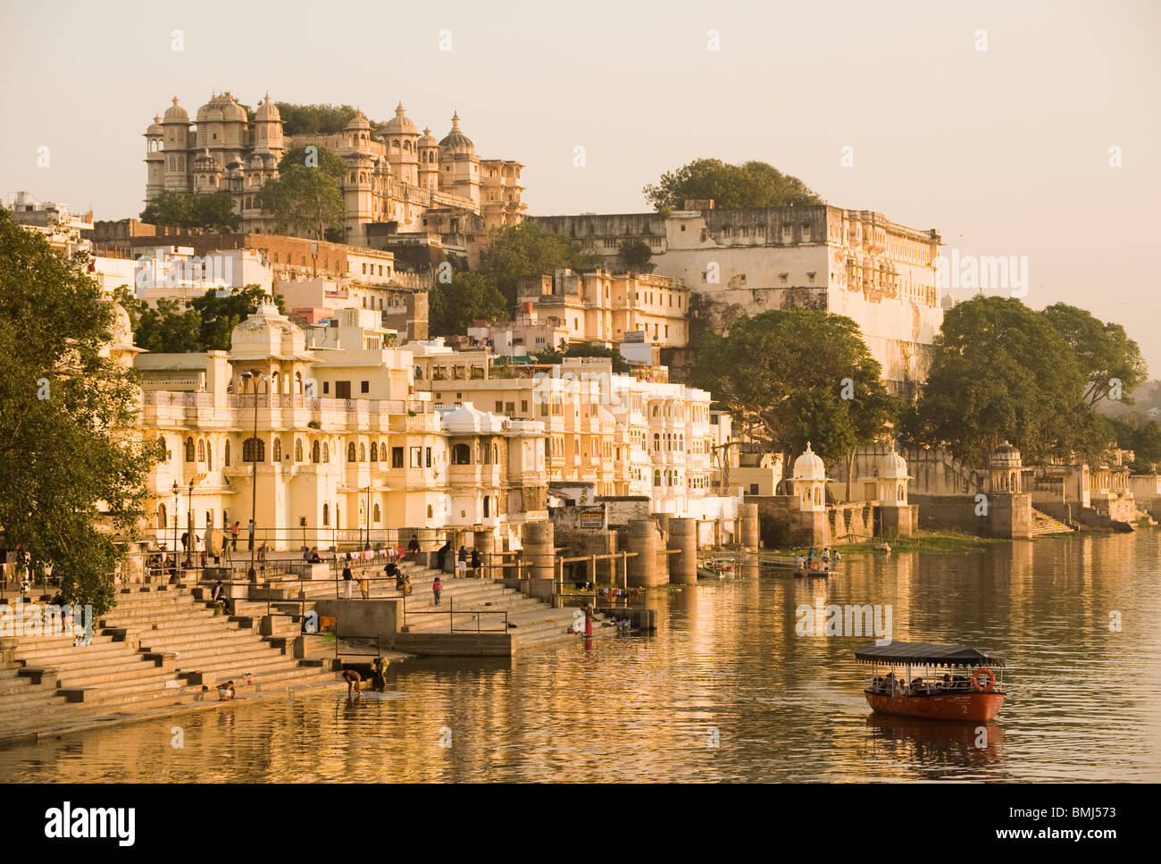 People on a boat ride on Lake Pichola Udaipur with the City Palace in the background in India Stock Photo