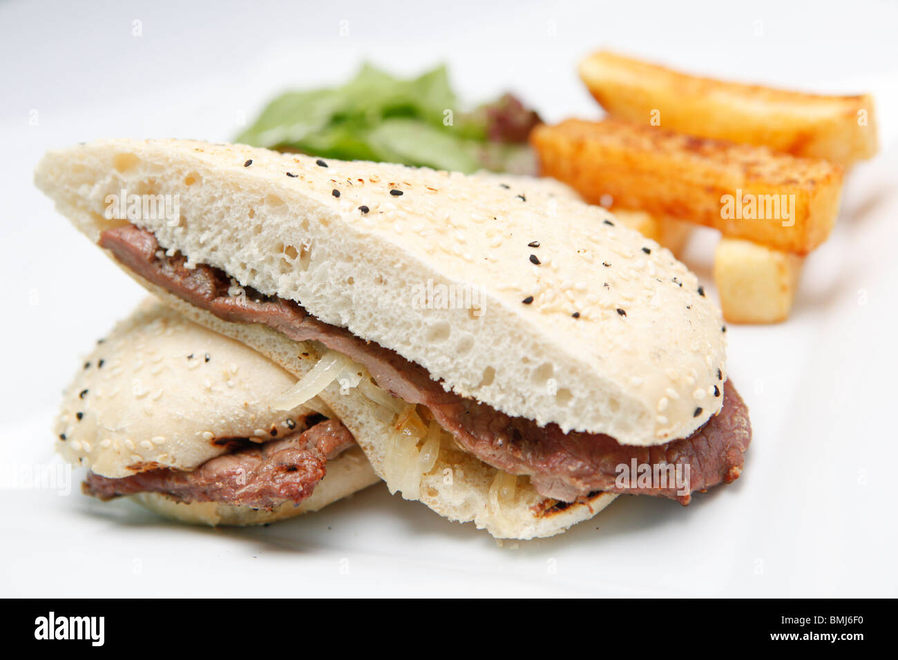 Steak and onion sandwich served as bar food, with salad and chips Stock