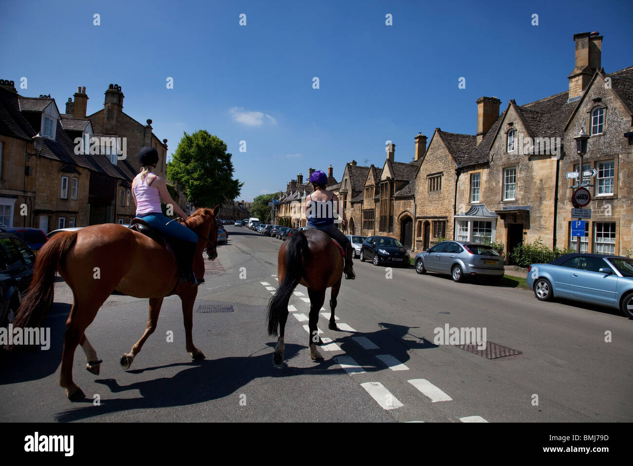 Horse riding past local stone buildings in Chipping Campden. The Cotswolds, Gloucestershire, UK. Stock Photo