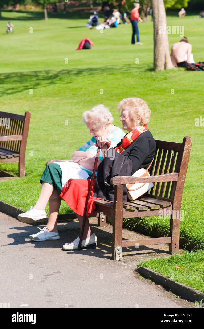 Golders Hill Park , tranquil or peaceful scene of two grey haired old ladies or women on park bench enjoying summer sunshine Stock Photo