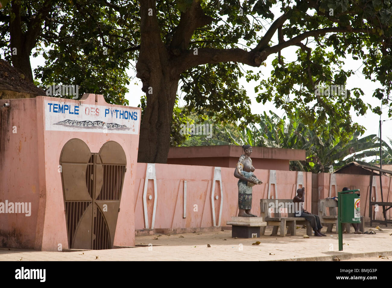 Africa, West Africa, Benin, Ouidah. Men sitting on benches beside statue in Ouidah, Benin. Stock Photo