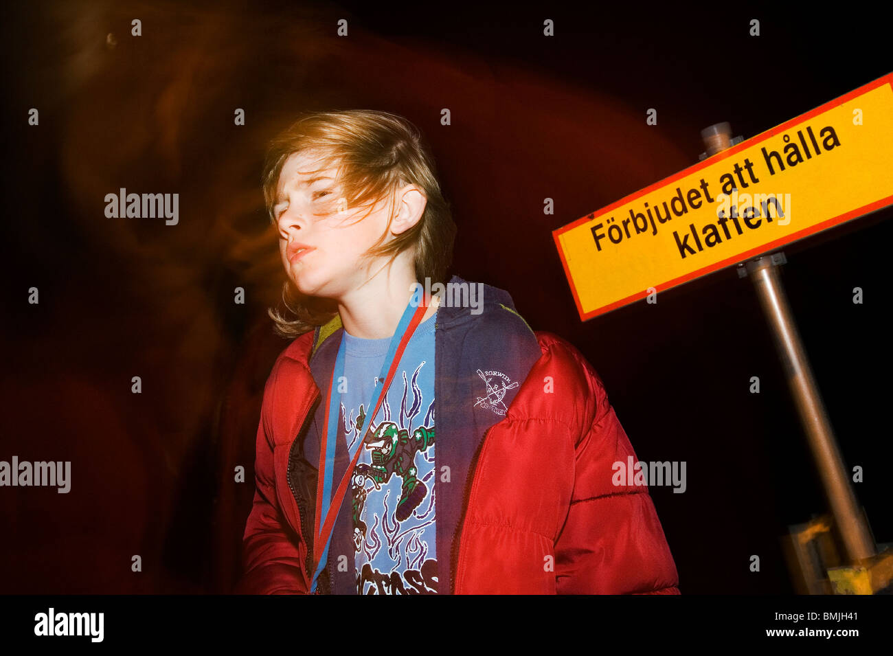 Boy by a sign at night, Finland. Stock Photo