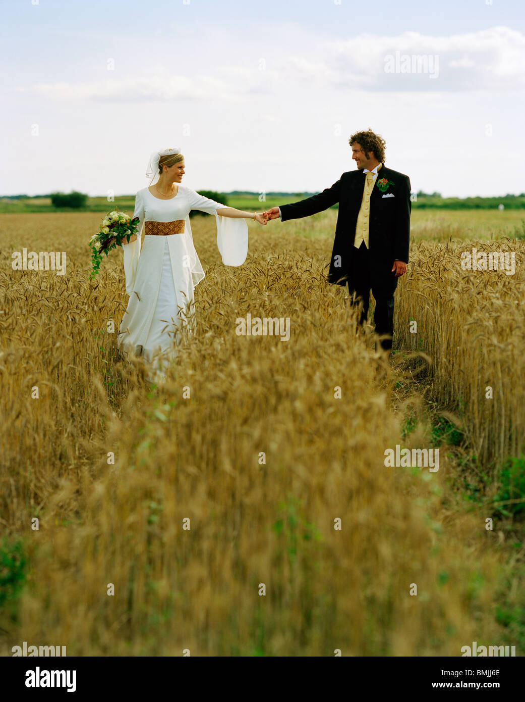 Scandinavia, Sweden, Oland, Bride and groom walking in field Stock Photo