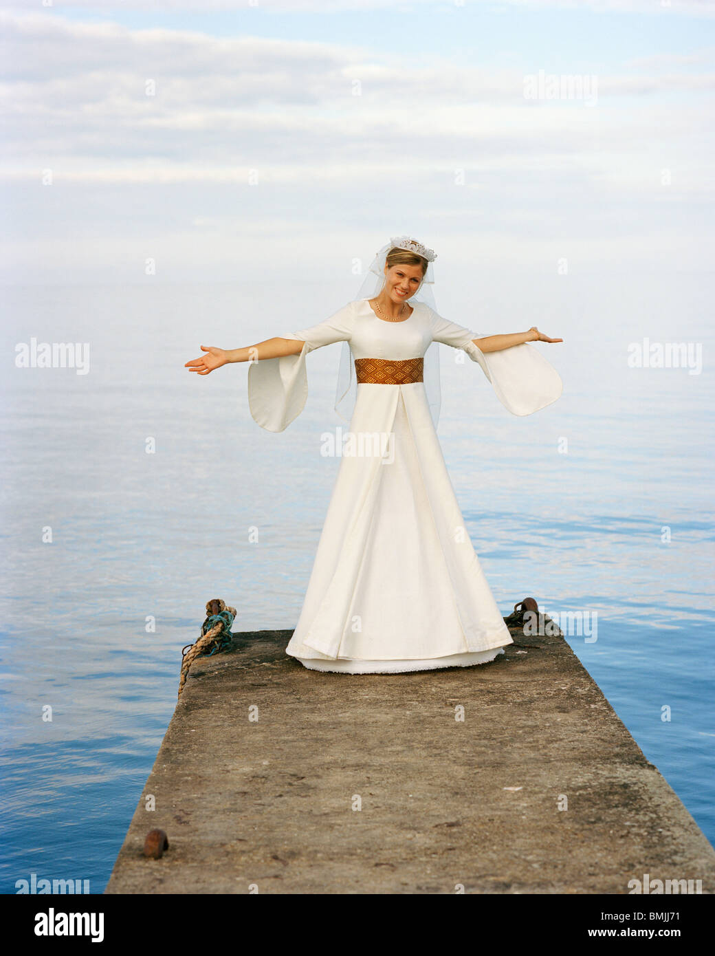 Scandinavia, Sweden, Oland, Bride standing on jetty arms outstretched, smiling, portrait Stock Photo