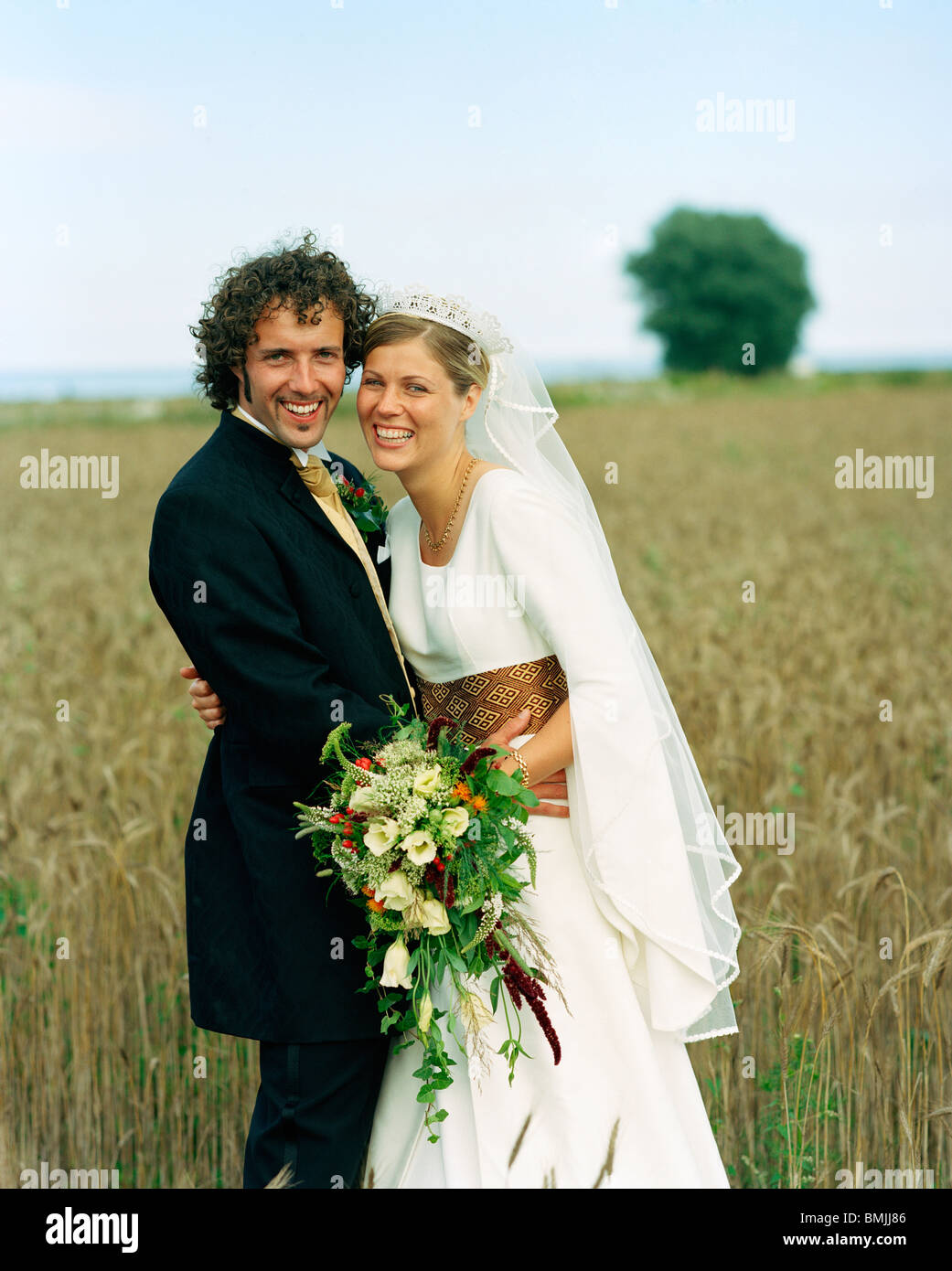 Scandinavia, Sweden, Oland, Bride and groom standing in field, smiling, portrait Stock Photo