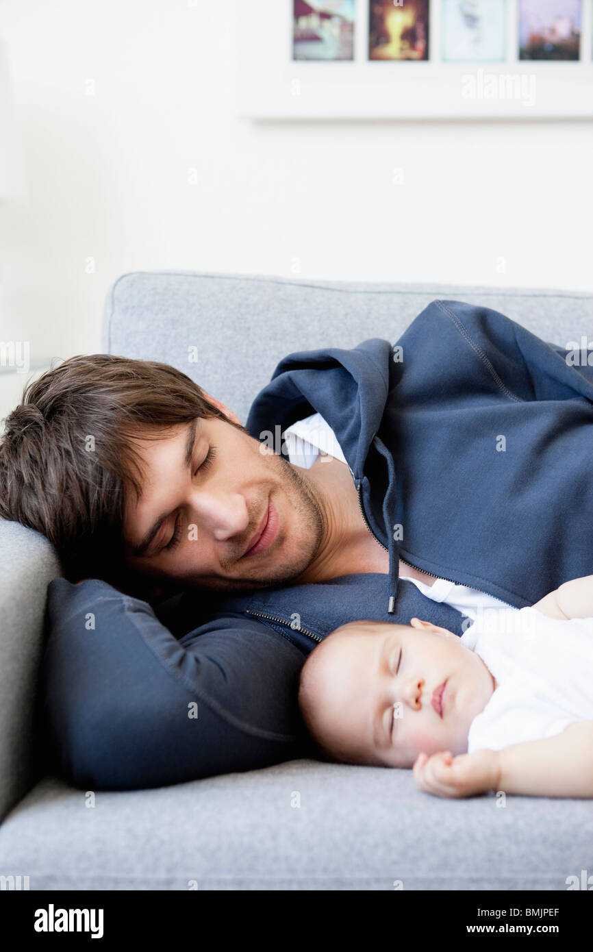 Father and baby sleeping on couch Stock Photo