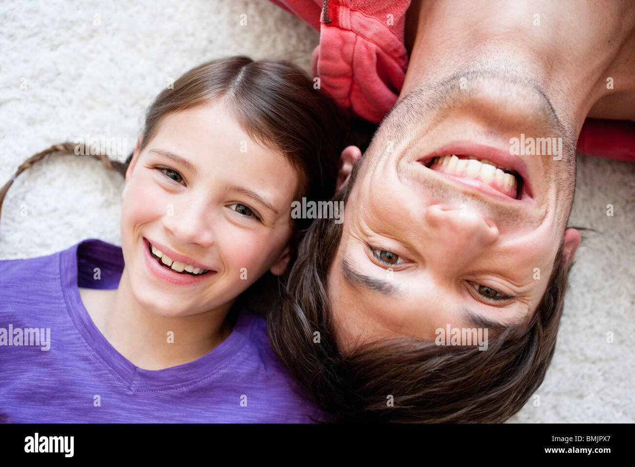 Father and girl lying on carpet Stock Photo