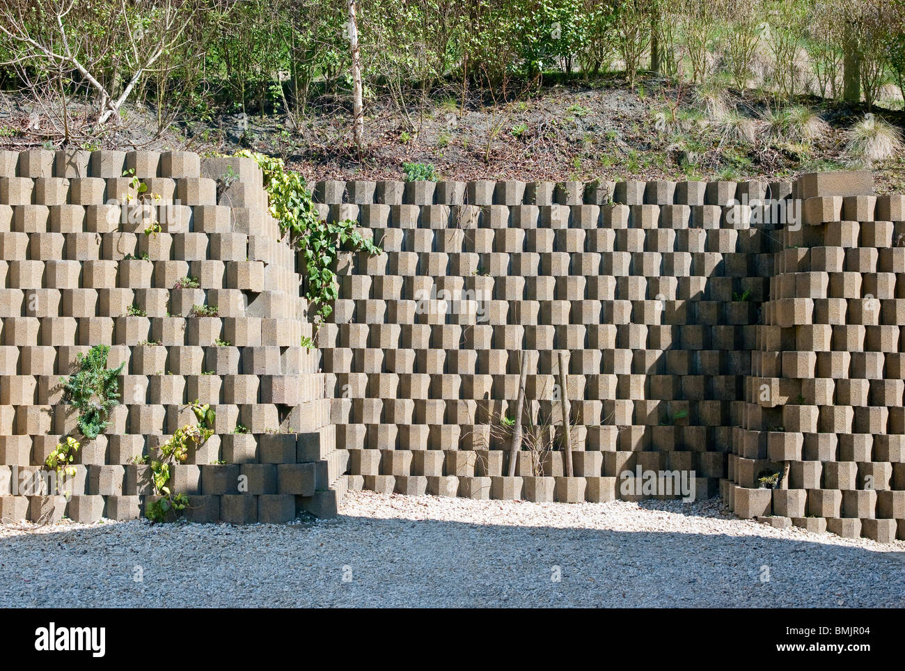 Neat concrete block retaining wall at bottom of hill-side garden Stock Photo