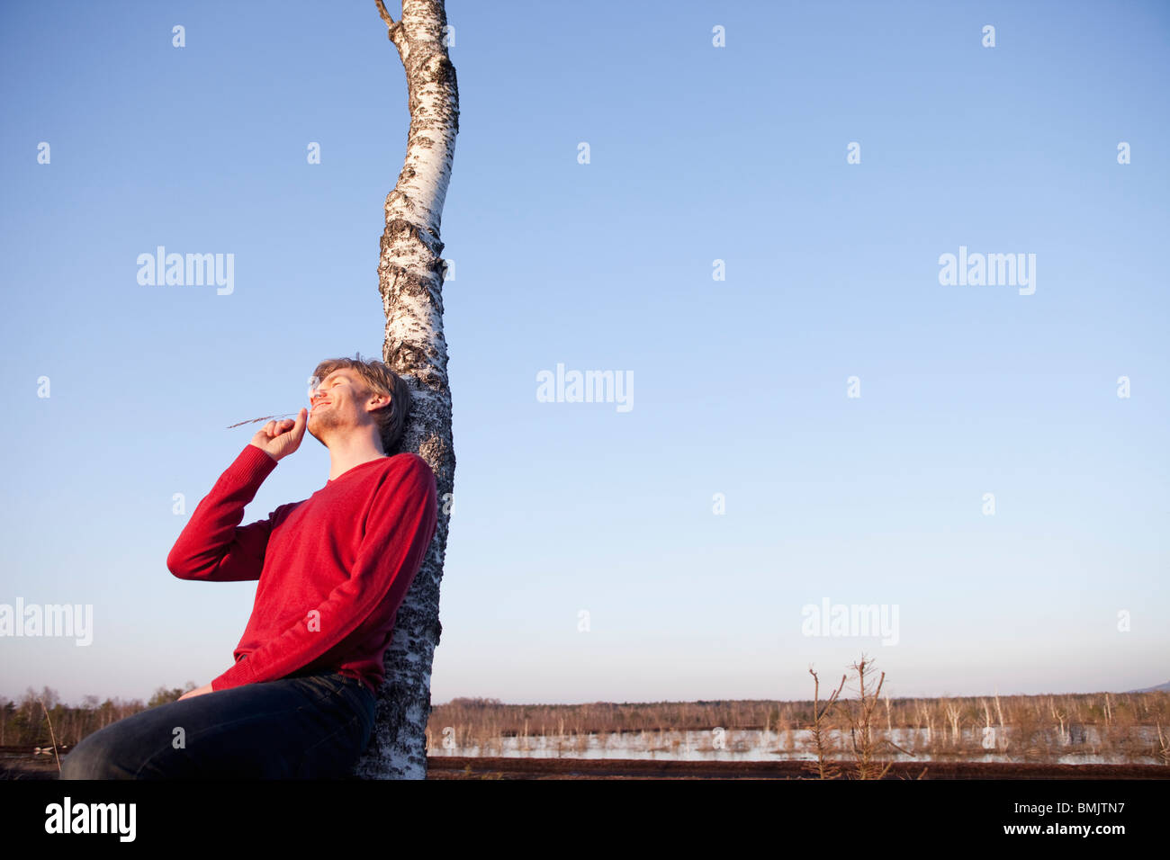 Man leaning back on tree Stock Photo