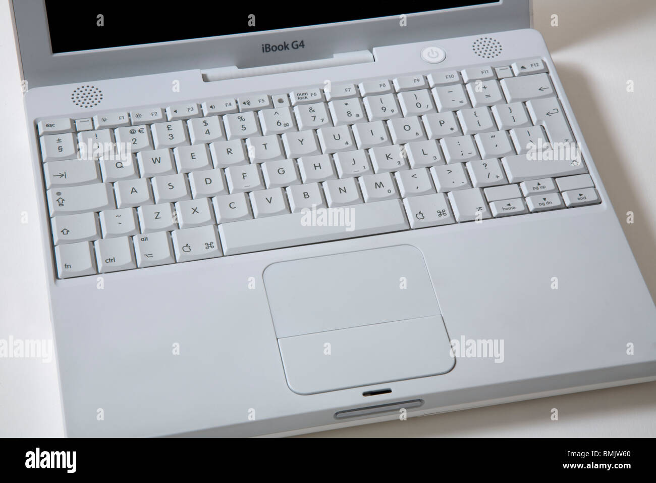 Open white Apple iBook G4 laptop / lap top computer; qwerty keyboard with scrolling TrackPad / trackpad / track pad. Stock Photo