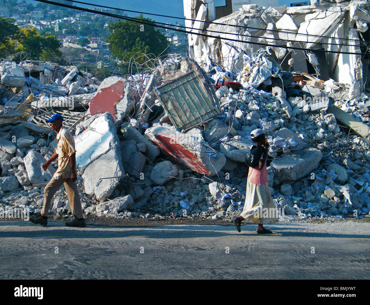 People walk past collapsed buildings in Port au Prince after the Haiti earthquake of Jan 12 2010 Stock Photo