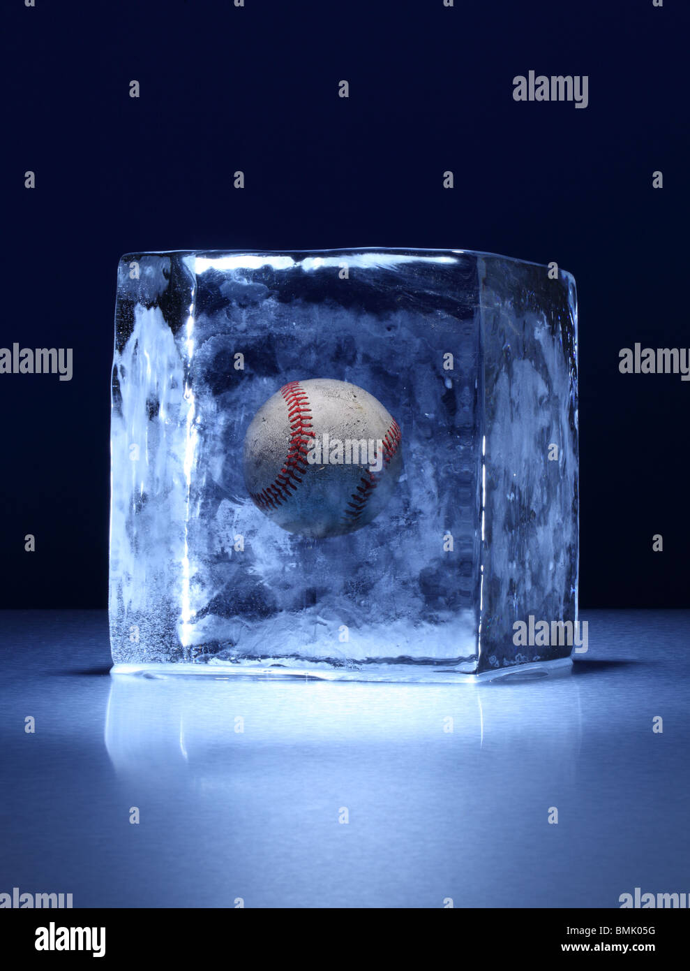 A frozen block of ice with baseball frozen inside on a metal surface Stock Photo