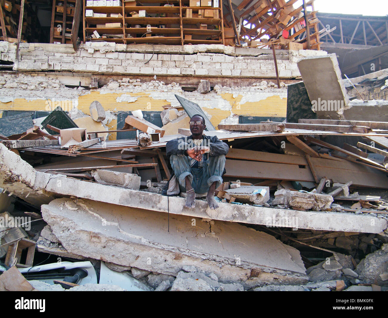 An elderly man sits in the rubble of a collapsed building in Port au Prince after the Haiti earthquake Stock Photo