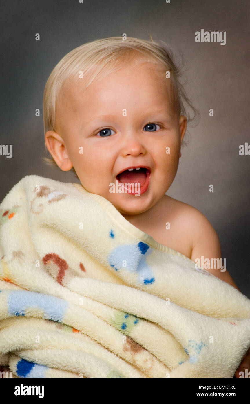 Portrait of a toddler wrapped up in a blanket and smiling Stock Photo
