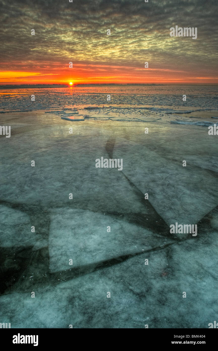 Sunrise across a frozen freshwater lake in Michigan, United States, North America with shifting ice sheets below the surface Stock Photo