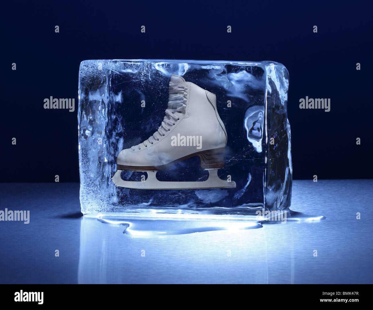 A frozen block of ice with a woman's figure skate frozen inside on a metal surface Stock Photo