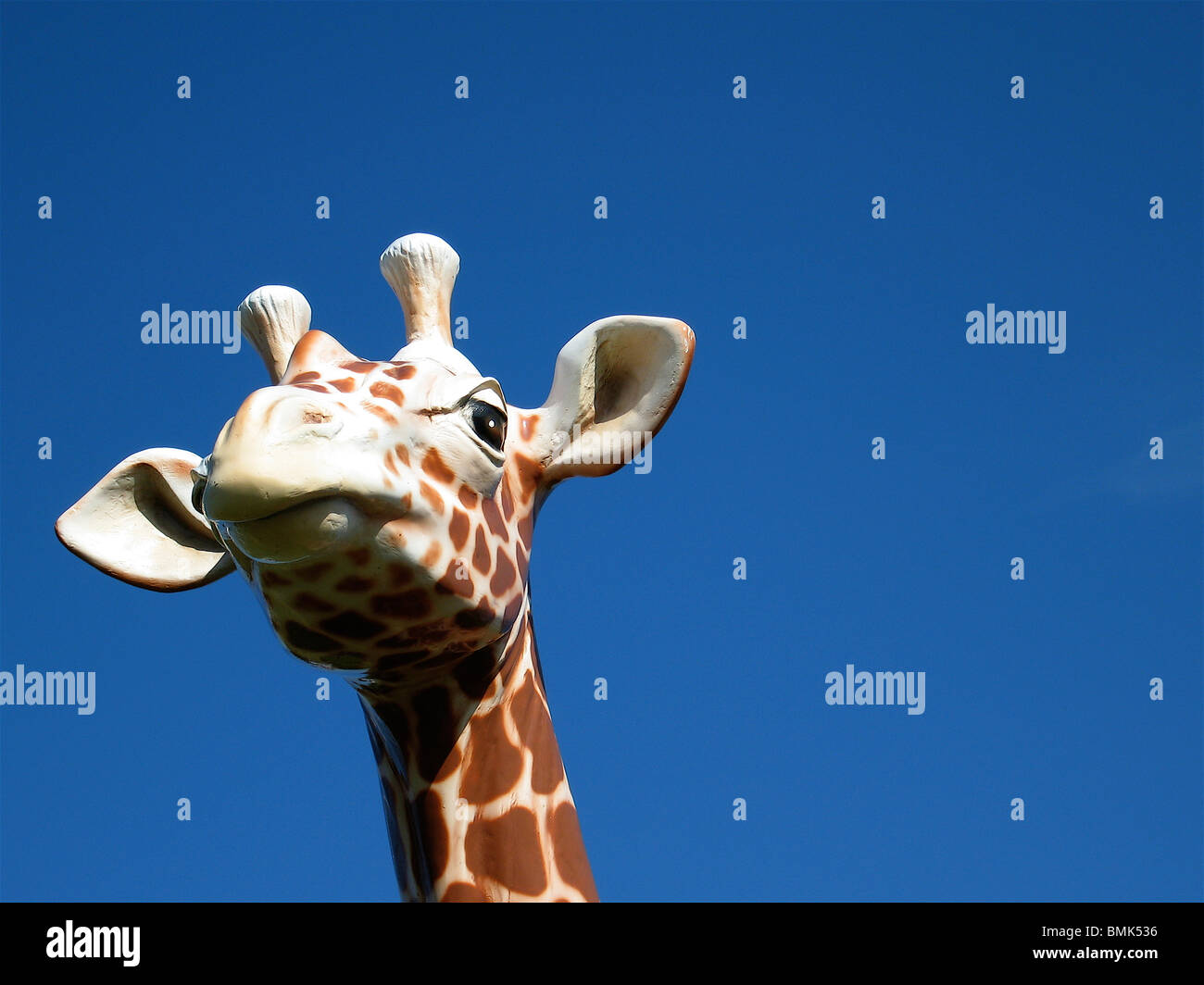 Plastic Giraffe against blue sky Stock Photo