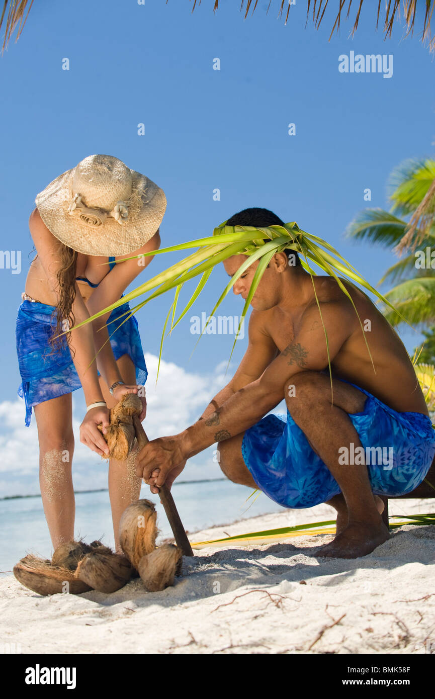 tahitian man is showing to a woman how to open and grate coconut containing milk Stock Photo
