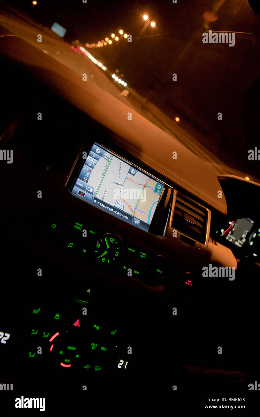 Interior of Range Rover car showing sat nav and dials on dashboard at night on motorway with traffic. UK Stock Photo