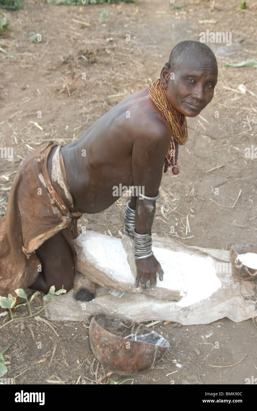 Ethiopia: Lower Omo River Basin, Chelete farms for Karo, woman grinding grain Stock Photo