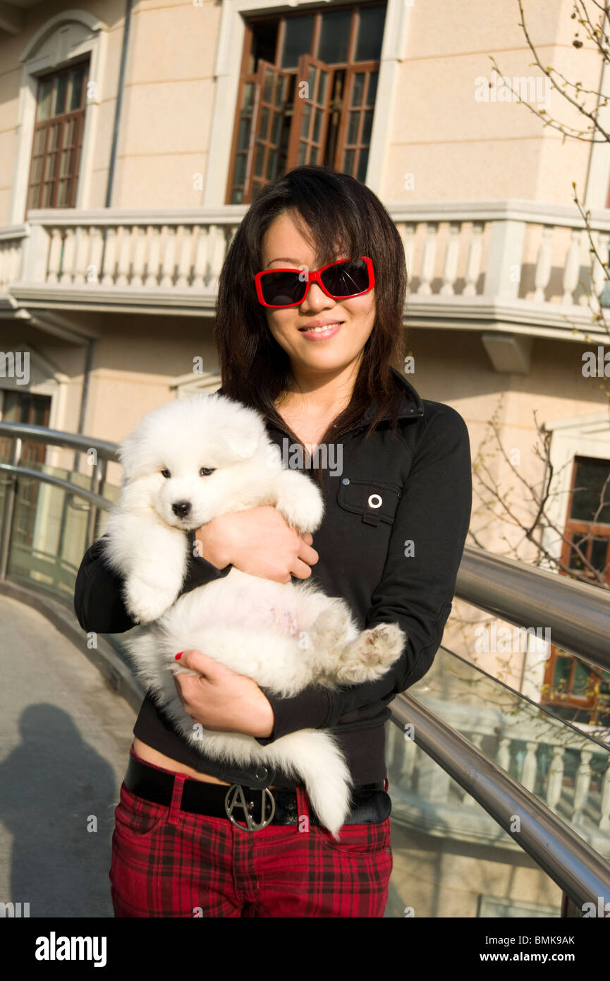 Fashionable young woman holding her pet pedigree dog, Shanghai, China