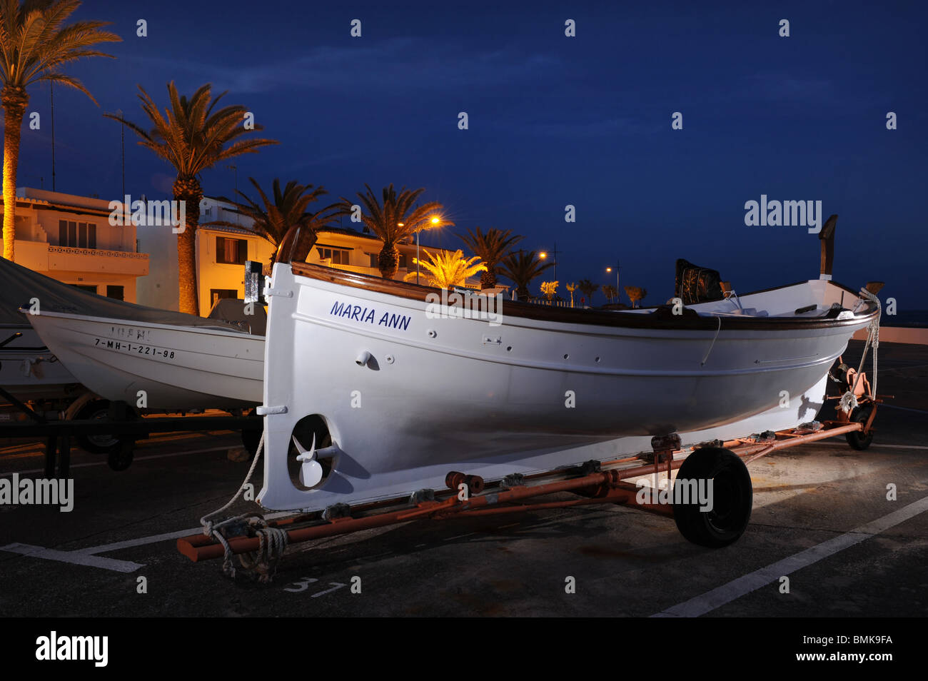 Small Spanish fishing boat, or Llaut, on trailer on the harbourside, S'Algar, Menorca, Spain, photographed at night Stock Photo