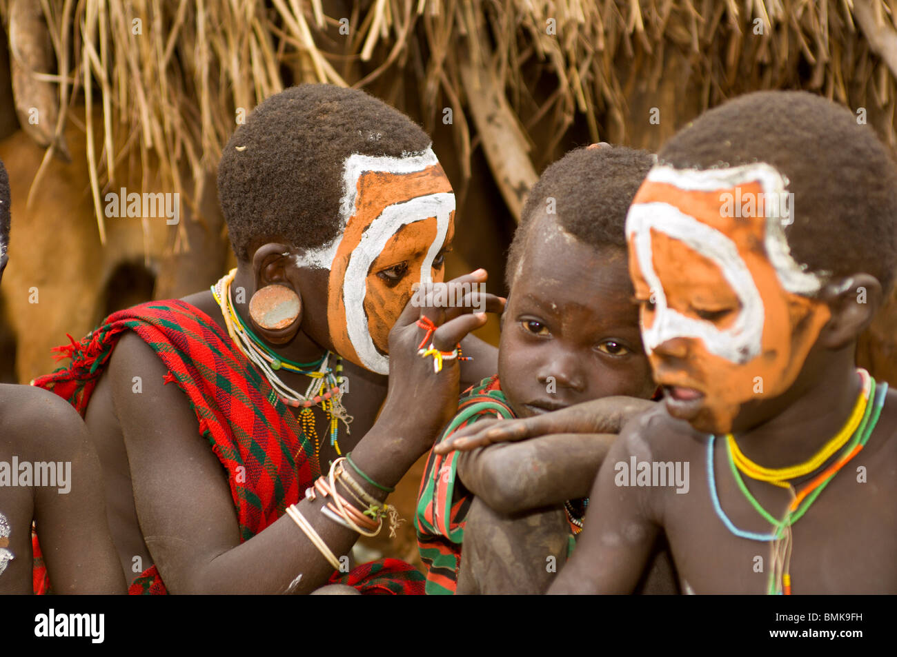 Africa, Ethiopia, Omo region, Kibish. Young Suri (Surma) tribe boy inspecting another boy's ear. Stock Photo