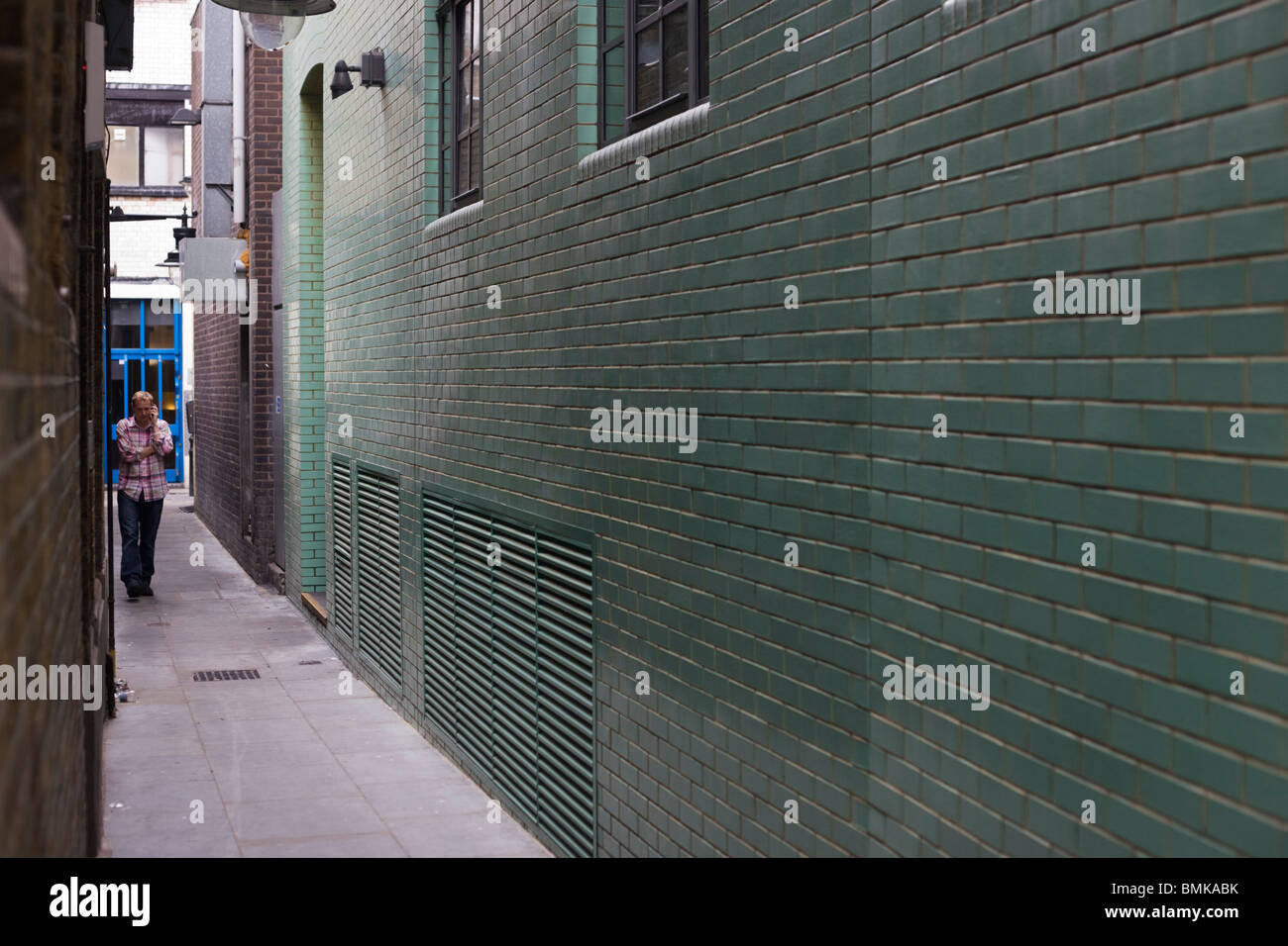 A man takes a discreet phone call in a narrow Soho alleyway outside offices in London. Stock Photo