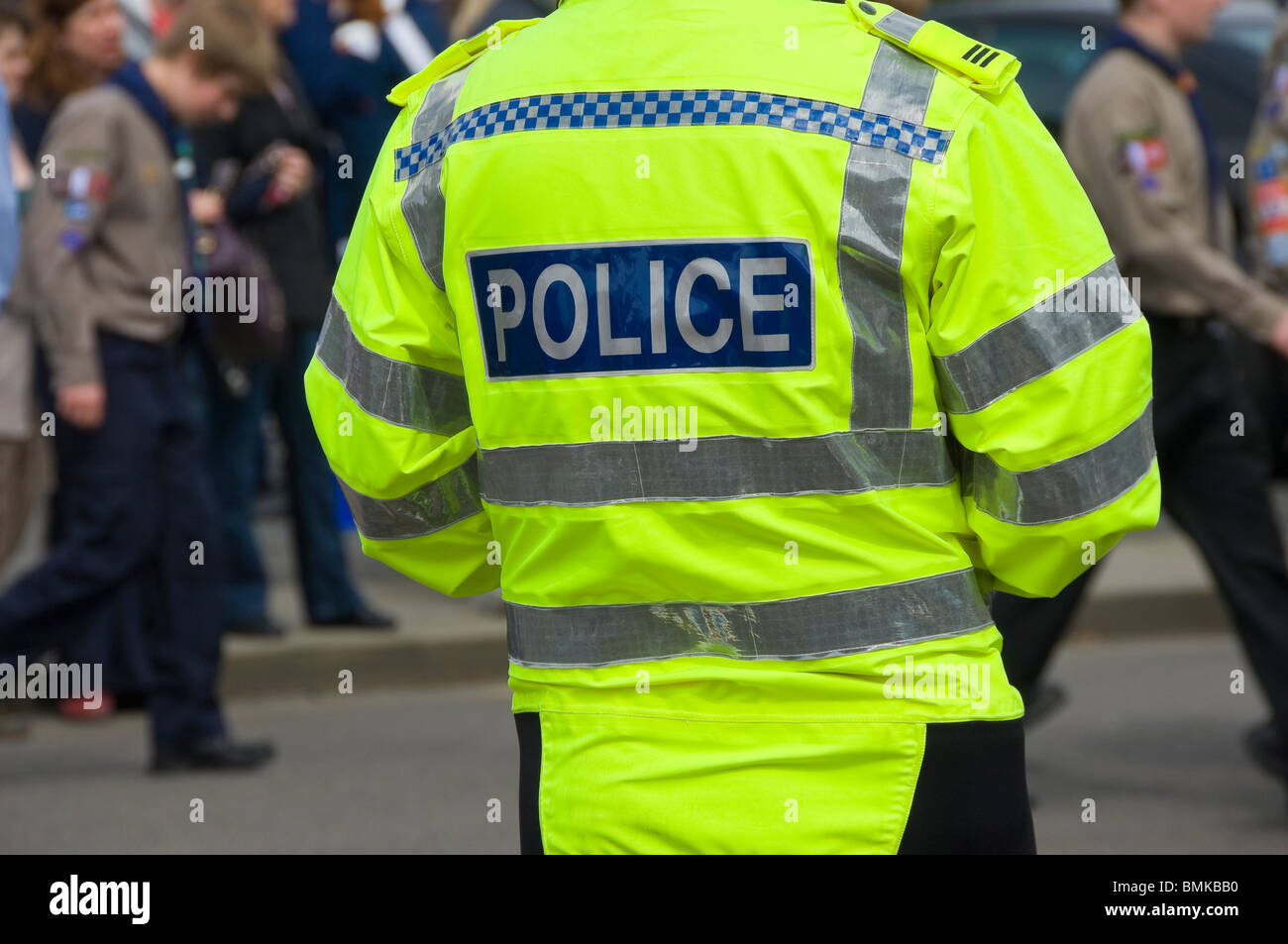 Close up of back rear view of British police officer cop on crowd control duty wearing fluorescent hi vis jacket England UK United Kingdom GB Britain Stock Photo