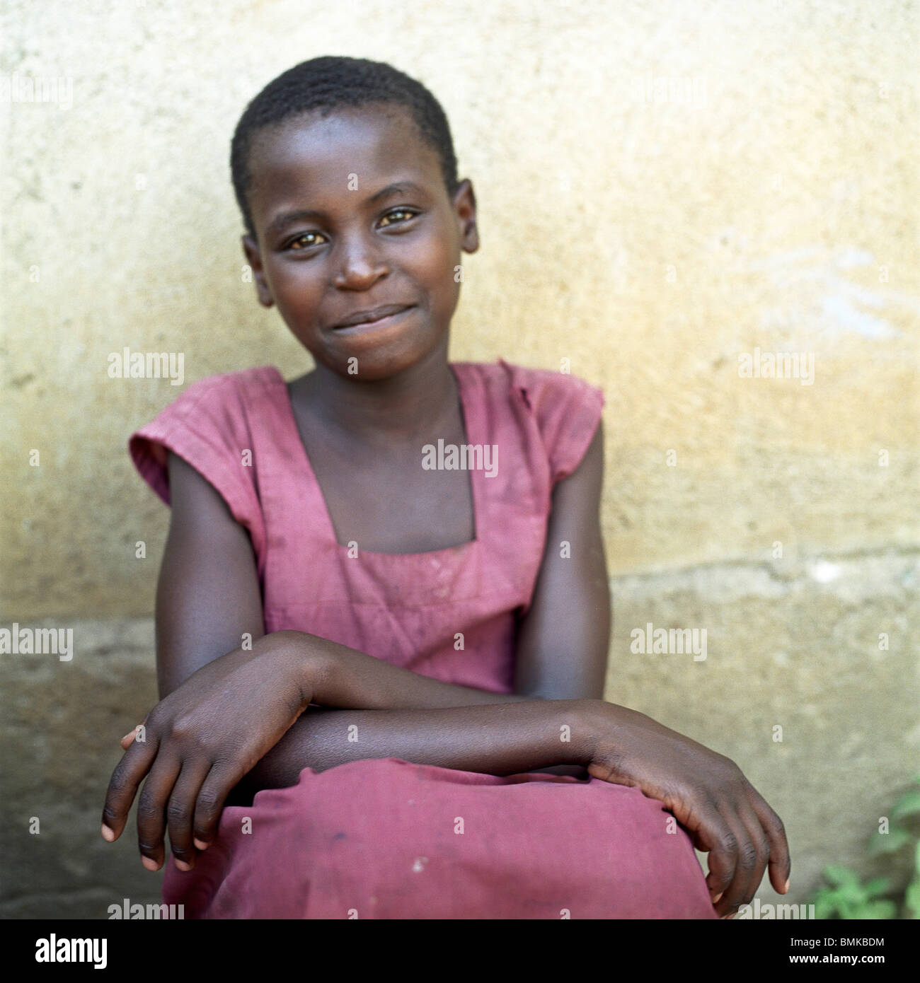 Kenyan girls student sits in front of a mud hut wearing school uniform ...