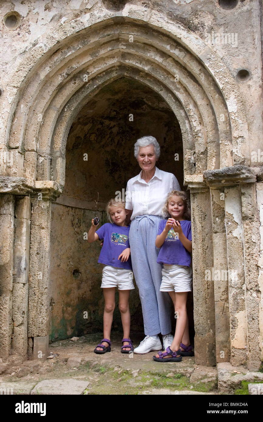 Africa, Kenya, Malindi. Grandmother and twins stand in a doorway to the Gedi ruins, a fifteenth century Arab-African town. Stock Photo