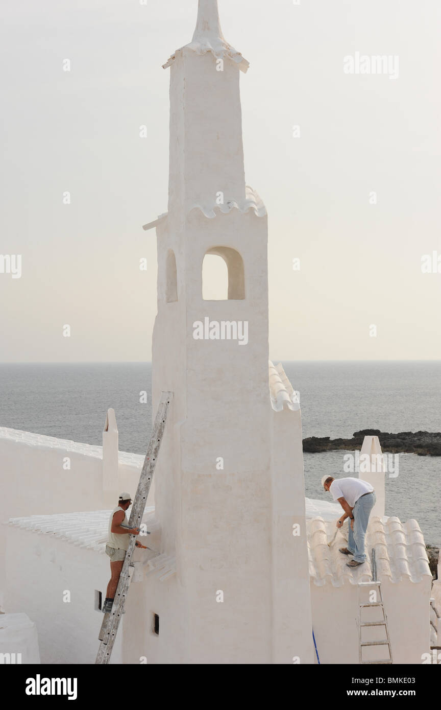 Painters whitewashing the bell tower of the small church in Binibeca, Menorca, Baleraric Islands, Spain Stock Photo