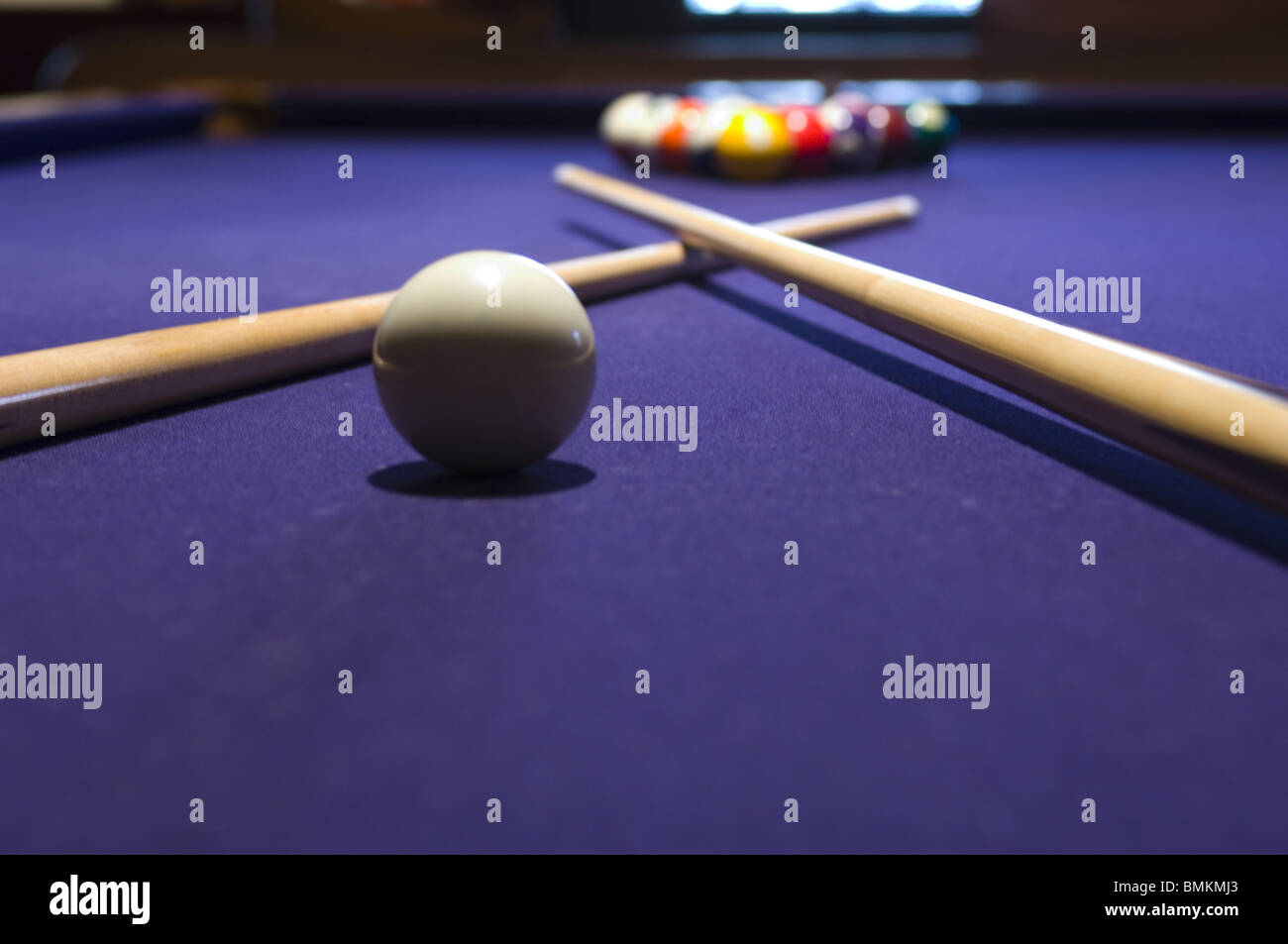 Closeup of a cue ball and pool sticks crossed over on a pool table Stock Photo Alamy