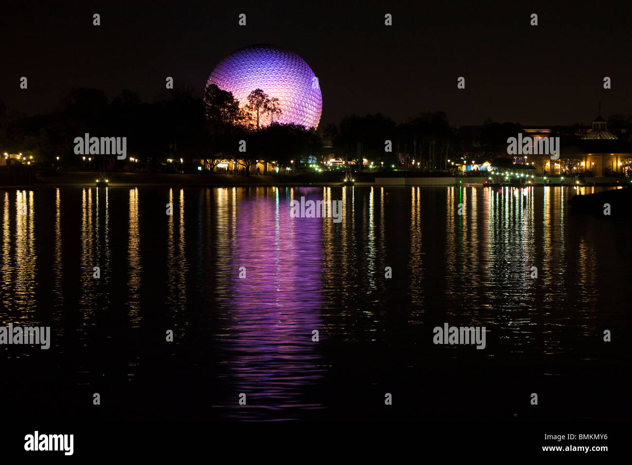 Geodesic dome of Spaceship Earth attraction lit with purple lights reflecting off lake at night in Walt Disney's Epcot Center Stock Photo