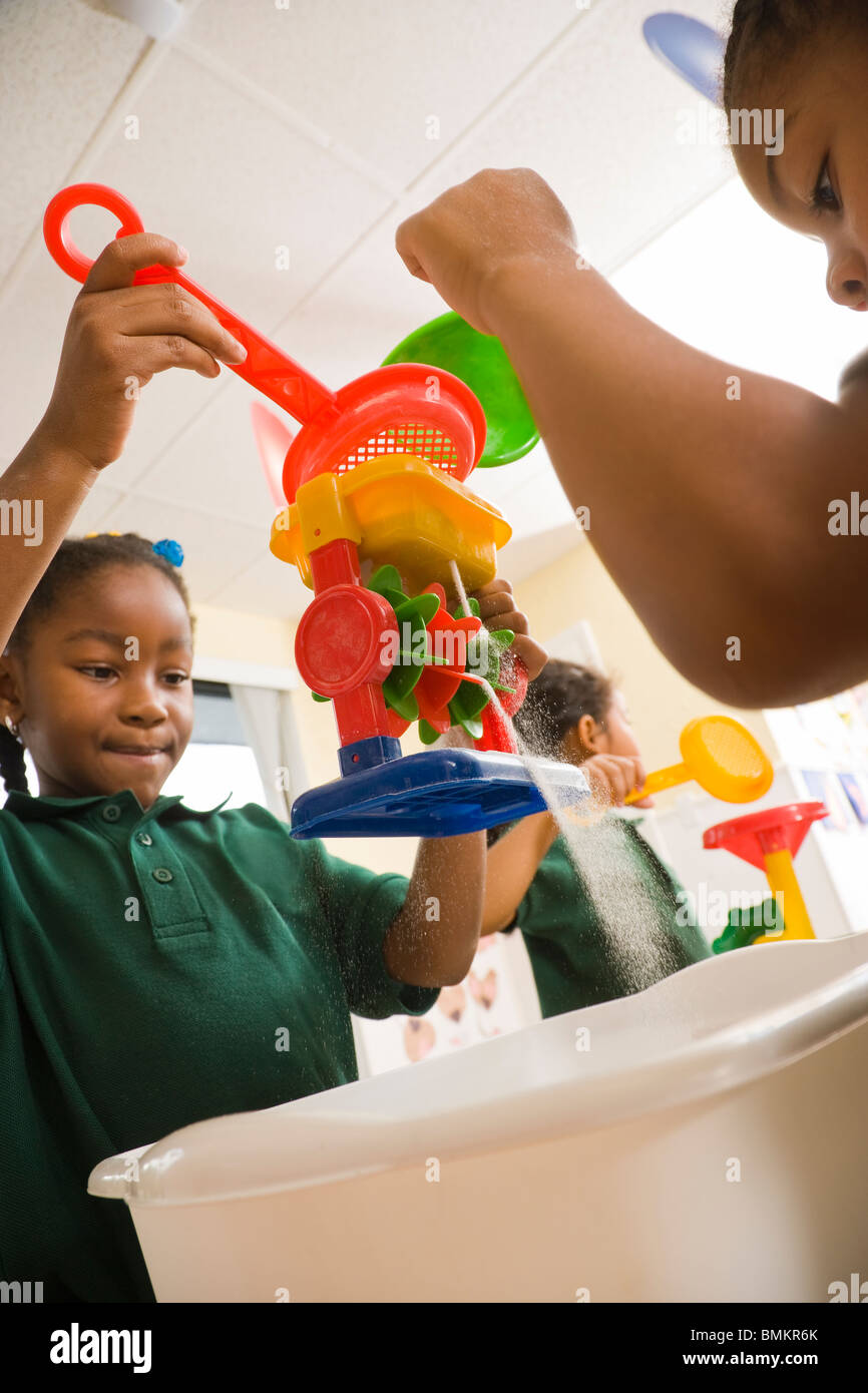 Three preschool girls playing with sand in classroom Stock Photo