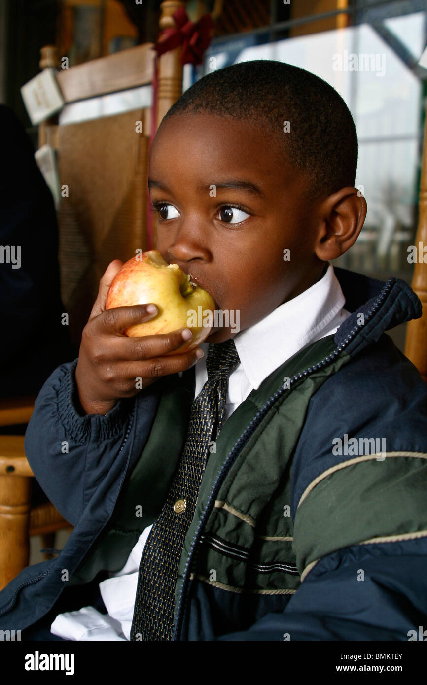 African American boy eating apple in front of Cracker Barrel Store and Restaurant in Florida Wearing a down jacket.MR  © Myrleen Pearson Stock Photo