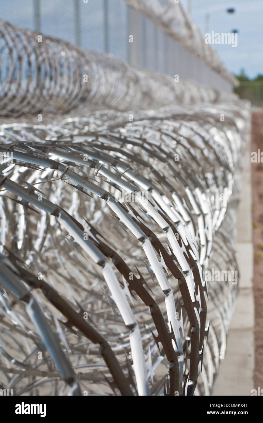 Rolls of stainless steel razor wire spirals keep prisoners away from chain link fence at correctional facility in Florida Stock Photo