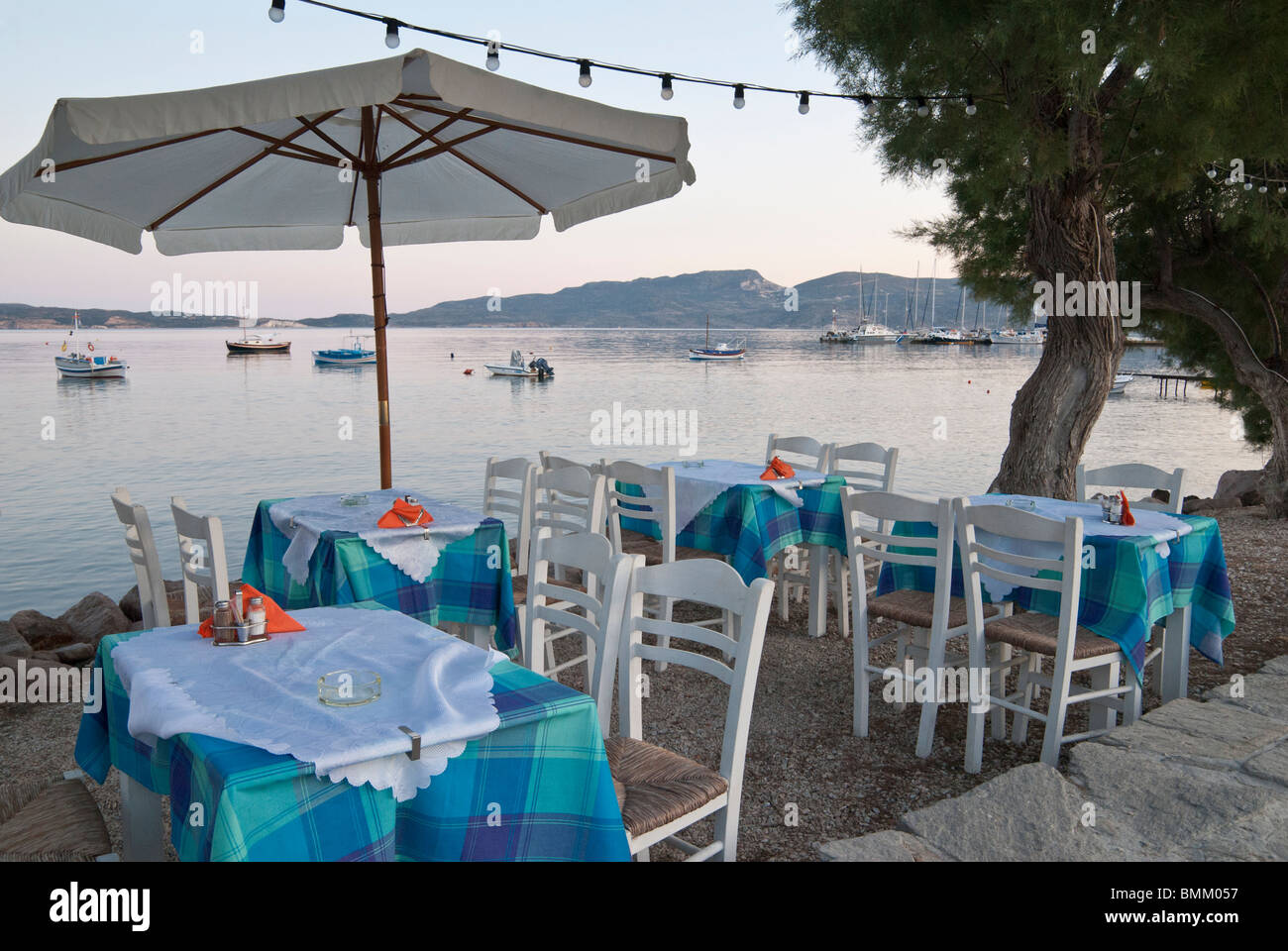Table and chairs on the waterfront at sunset, Adamas, Milos Island ...
