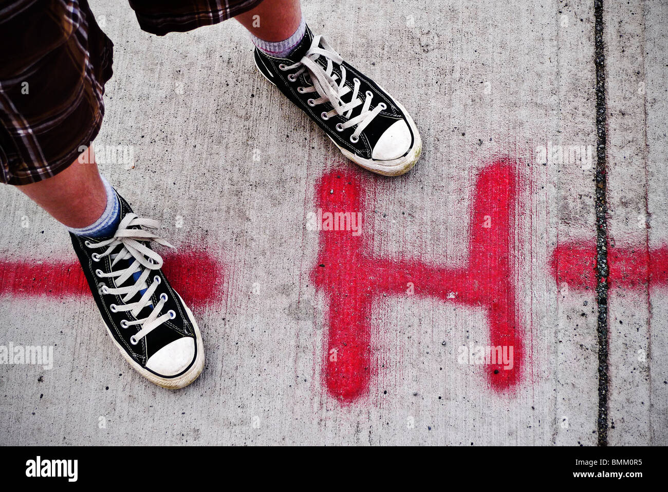 Urban youth with Converse high-tops standing beside spray painted H on  sidewalk Stock Photo - Alamy