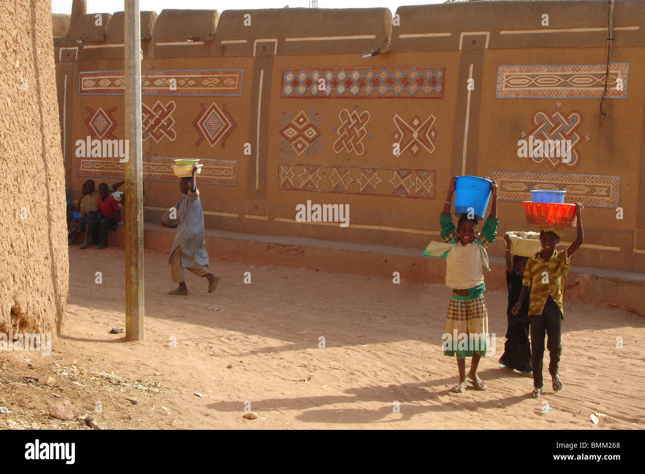 African children pausing in front of an african hausastyle house and