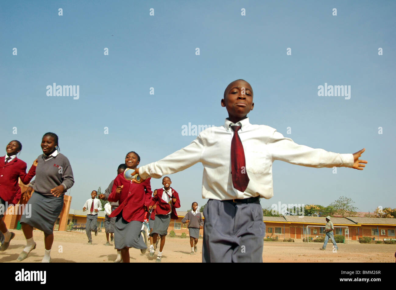 Nigeria, Jos, Schoolboys and schoolgirls in their purple and blue school uniform, running alltogether on a field. Stock Photo