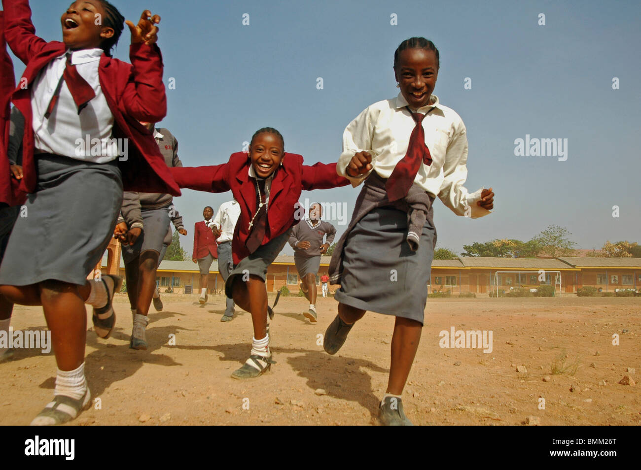 Nigeria, Jos, Schoolboys and schoolgirls in their purple and blue school uniform, running alltogether on a field. Stock Photo