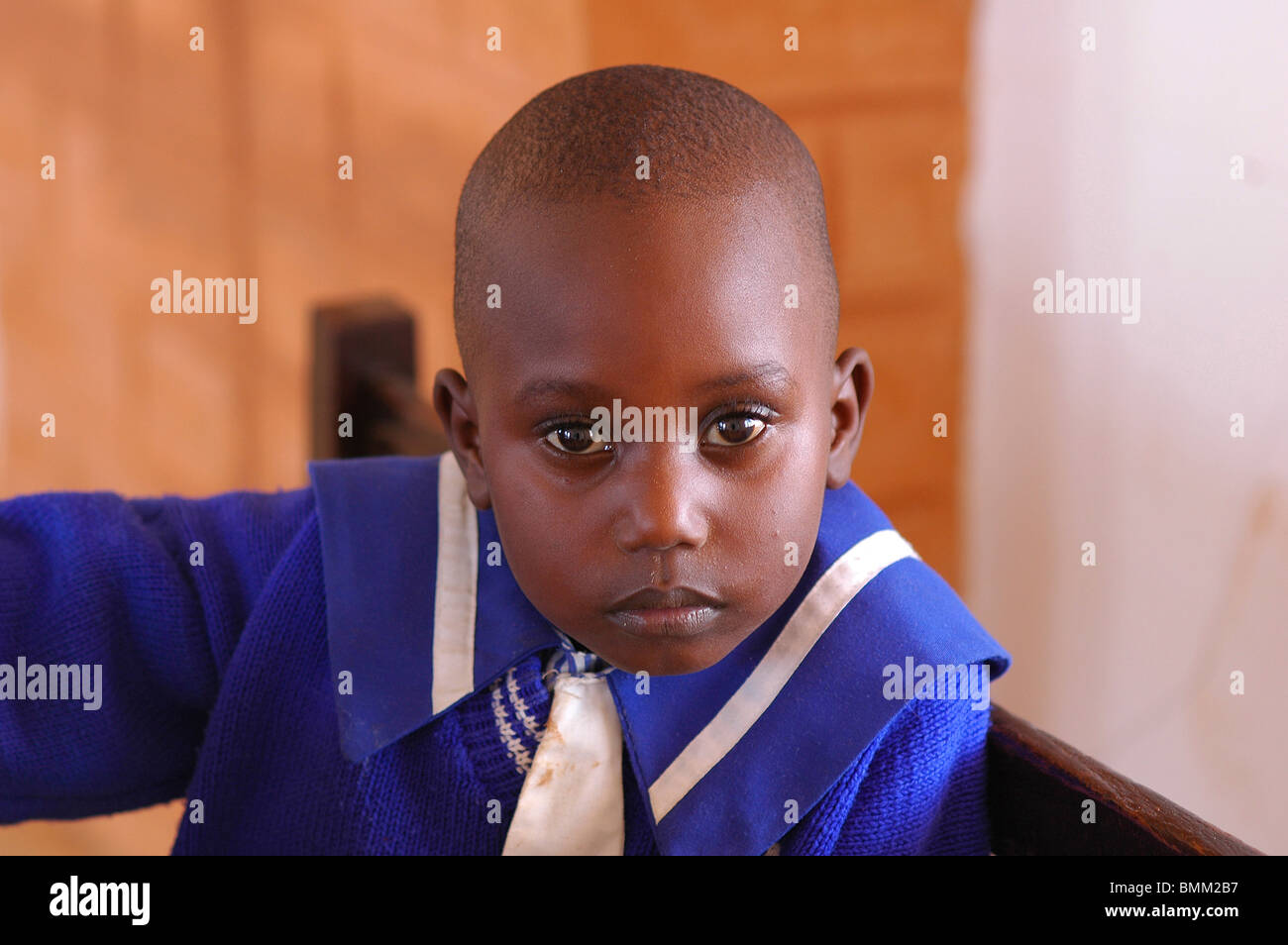Nigeria, Jos, Portrait of a black child wearing a blue navy style shirt, at a wooden desk, Stock Photo