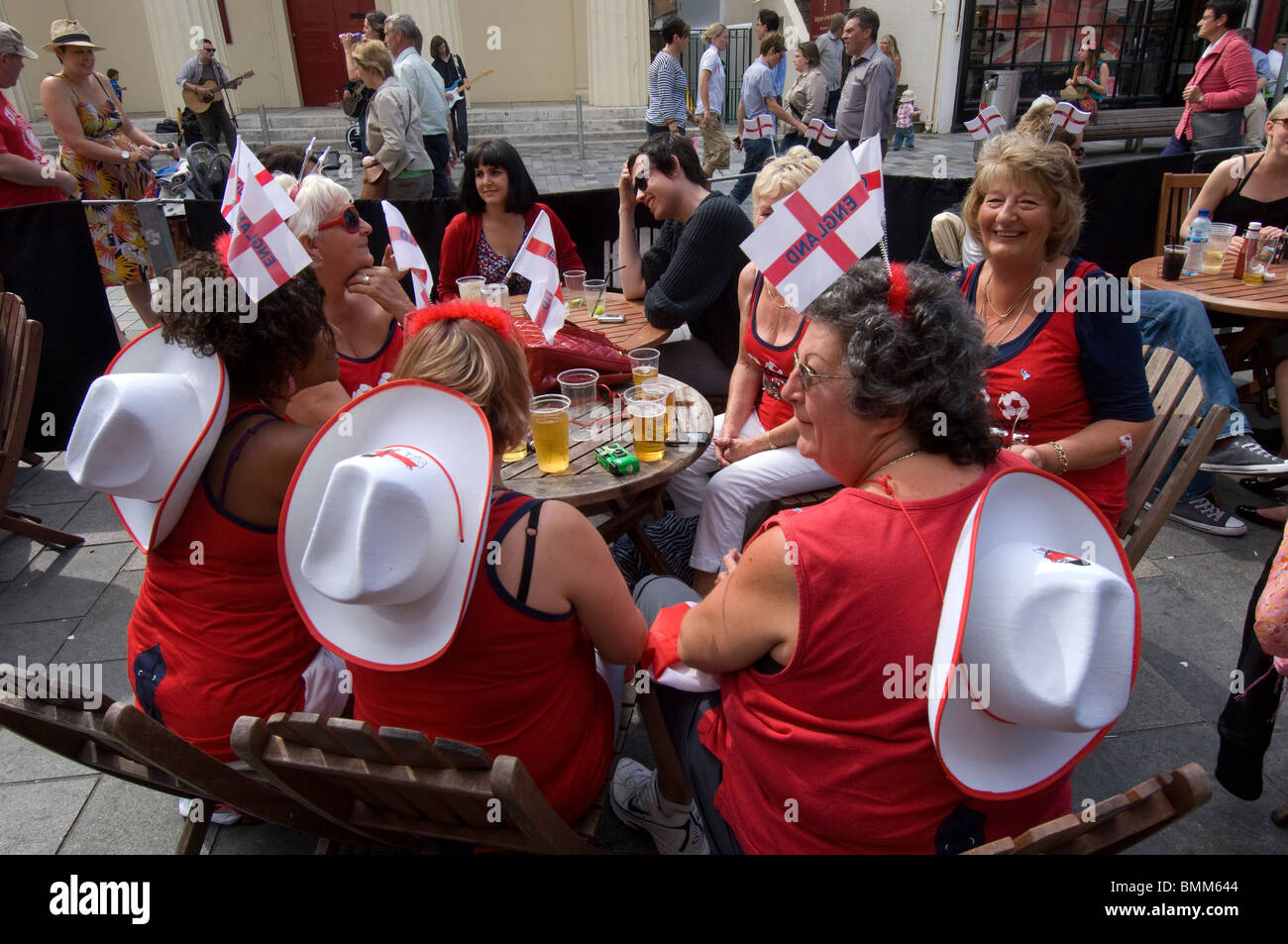 Middle aged women, England Football supporters, drinking before a game, wearing matching red and white shirts and hats with flag Stock Photo