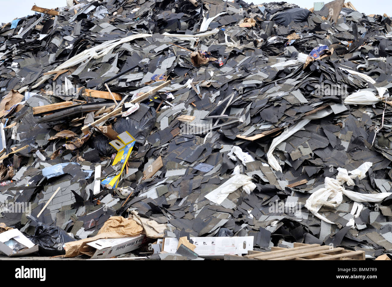 Big pile of asphalt roofing shingles and trash at landfill Stock Photo