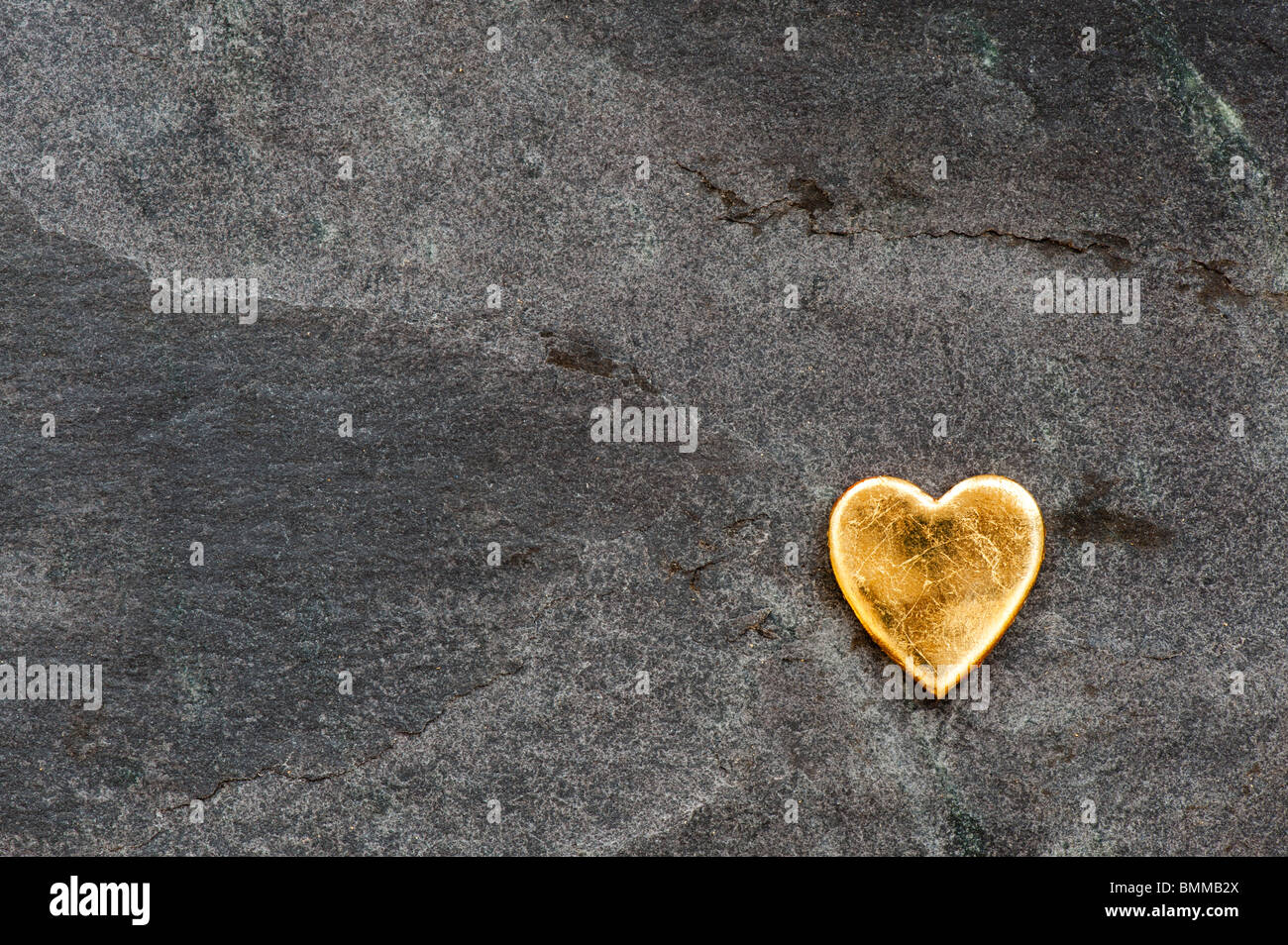 Gold heart shape against slate background Stock Photo