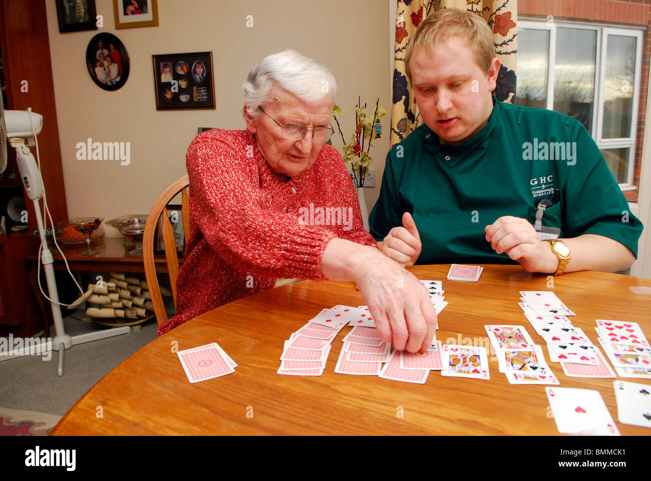 Care worker playing cards with an elderly lady in residential care home