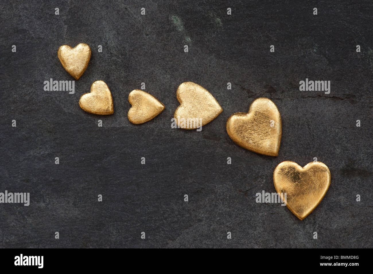 Gold heart shapes against slate background Stock Photo